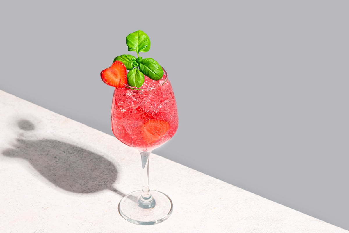 Strawberry summer cocktail with heart shaped strawberry on neutral background
