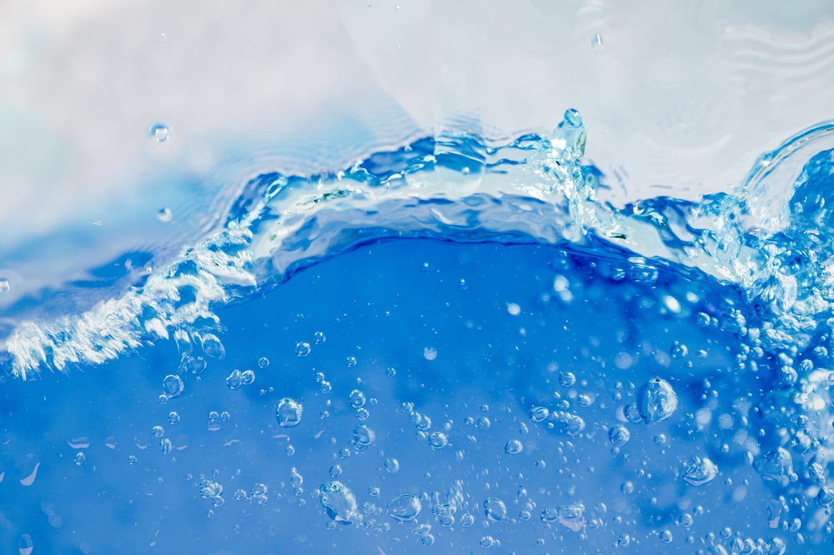 Clear blue water surface texture with ripples and sunlight reflections